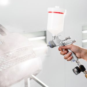 worker painting a car black blank parts in special garage, wearing costume and protective gear