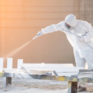 worker painting a mechanical part with airless spray