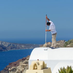 Man stays on the white roof and paints it